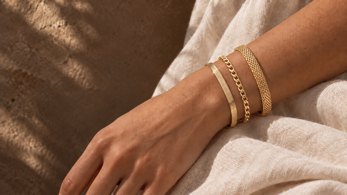 Gold herringbone, 3mm curb and mesh bracelets on a wrist